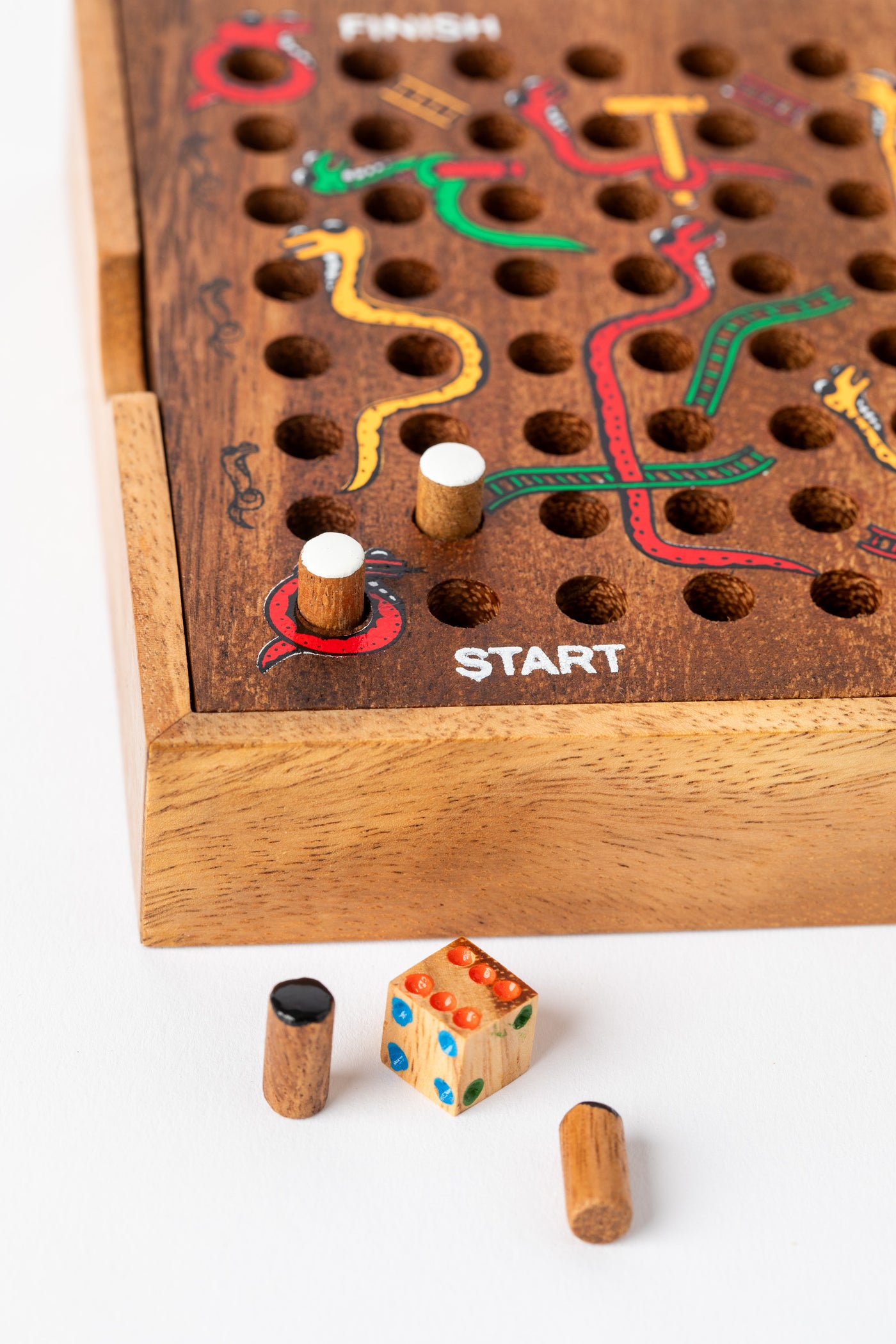 Start section of handmade wooden snakes and ladders board with painted designs and pegs — handcrafted family board game.
