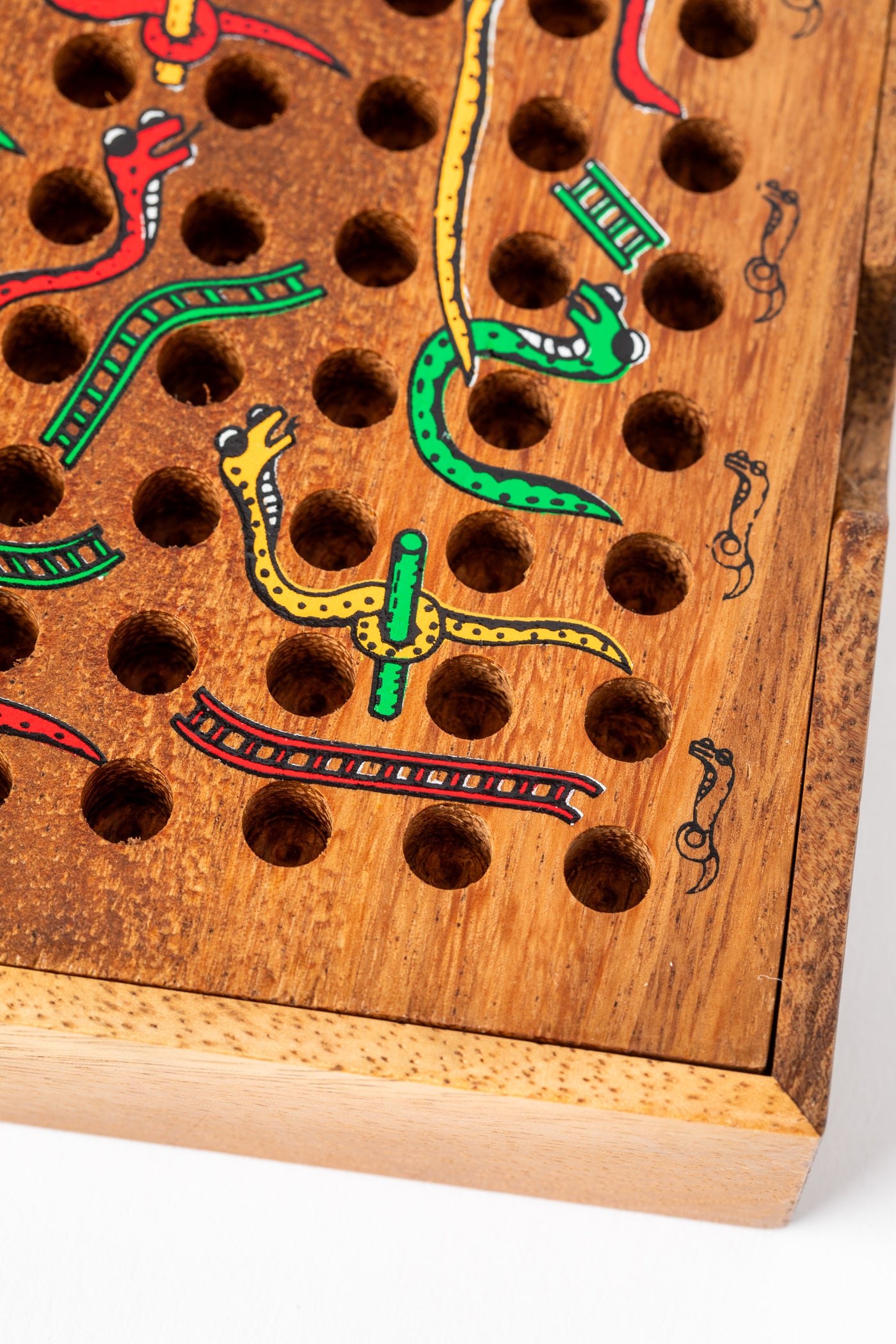 Colorful snakes and ladders painted on a natural wooden board — handmade eco-friendly game for kids and families.