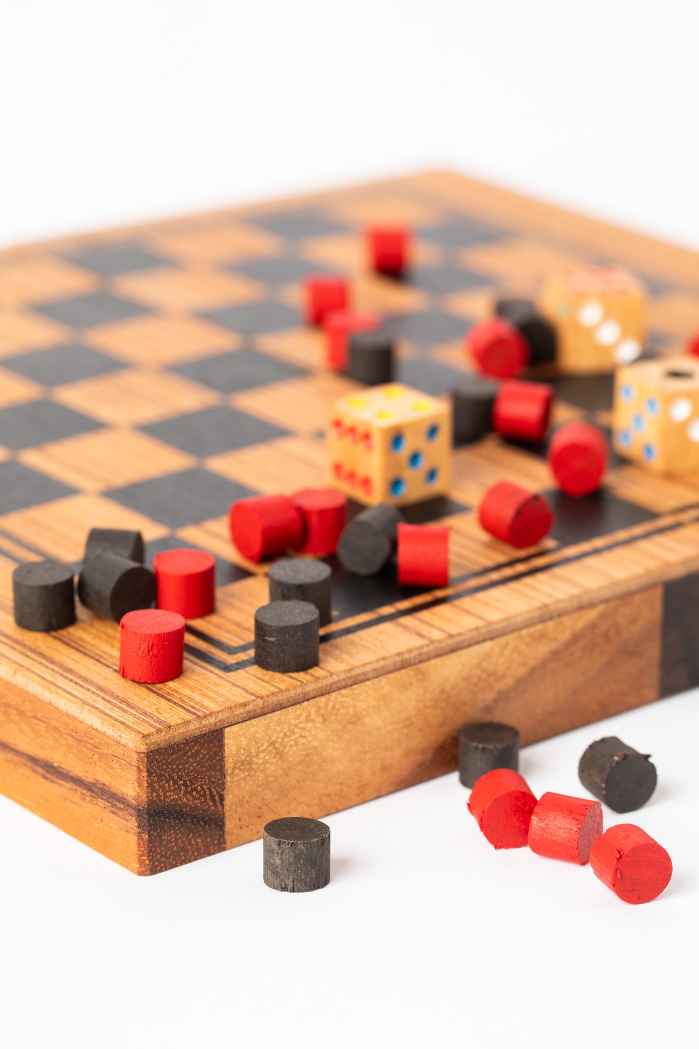 Colorful red and black wooden checkers pieces splayed on handmade board — eco-friendly family game.