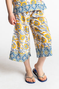 Louisa age 7 wearing Penny Lane Contrast Hem Kids Pants in sunflower print, size Small