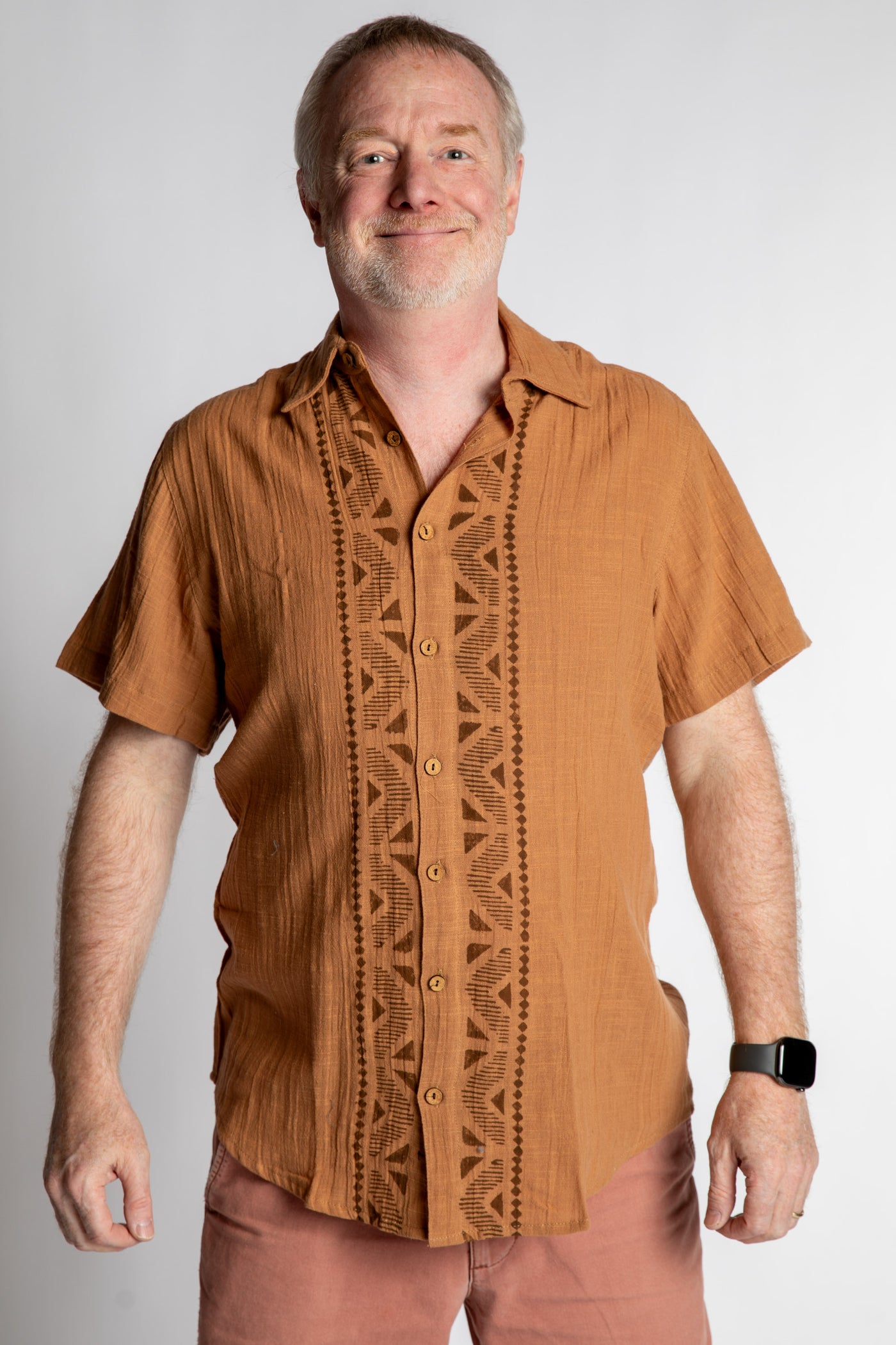 Chris, 5'7", wearing the Chandani Cotton Button Up in orange brown, size M