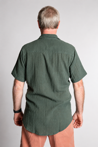 Chris, 5'7", wearing the Chandani Cotton Button Up in moss green, size M