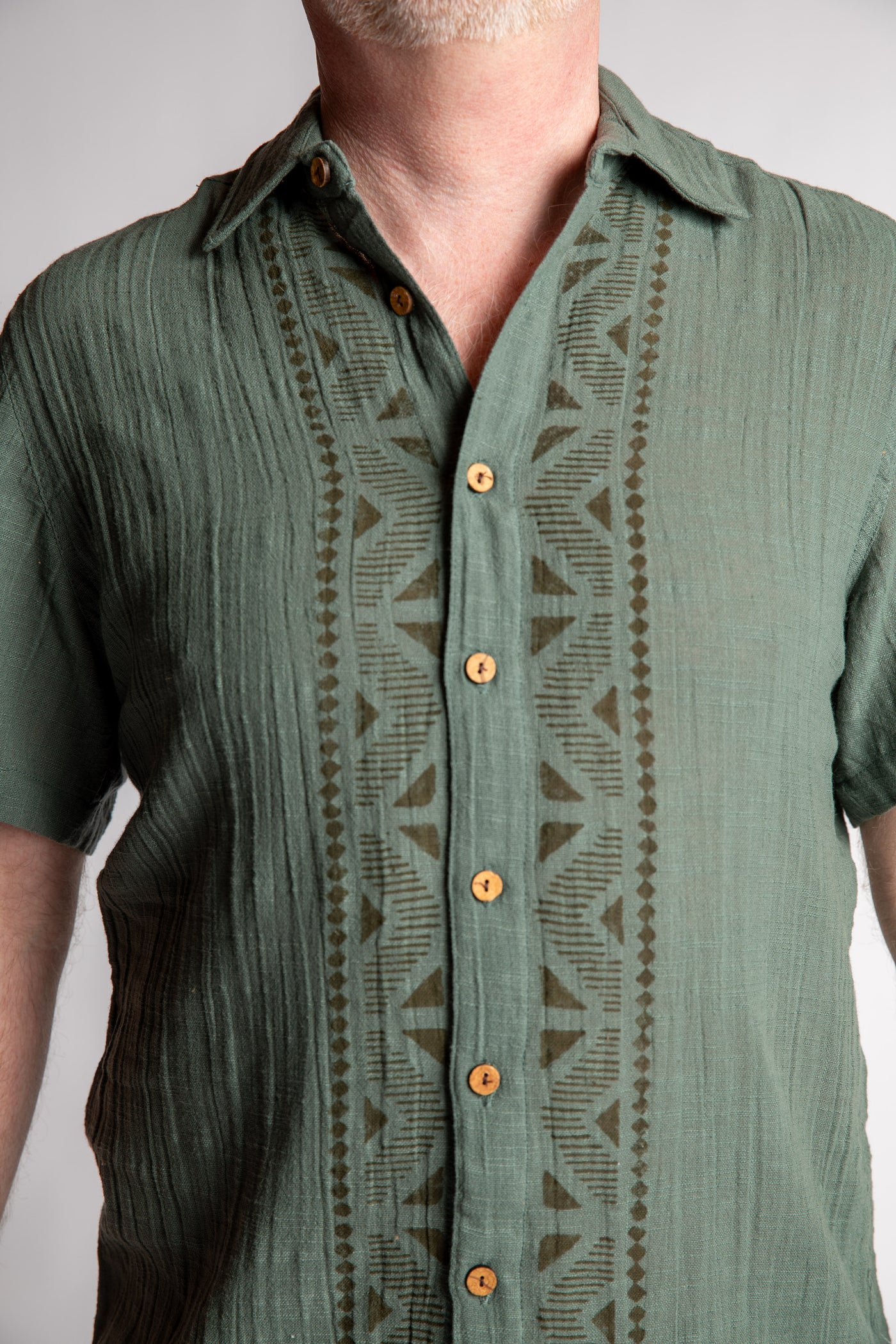 Chris, 5'7", wearing the Chandani Cotton Button Up in moss green, size M