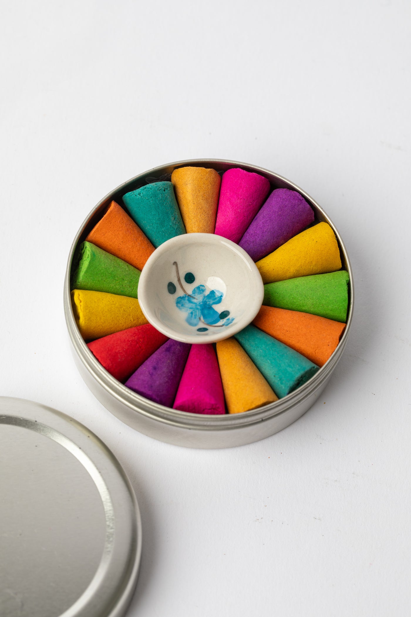 Round metal tin of Rainbow Cone Incense Wheel with colorful incense cones arranged around ceramic burner dish