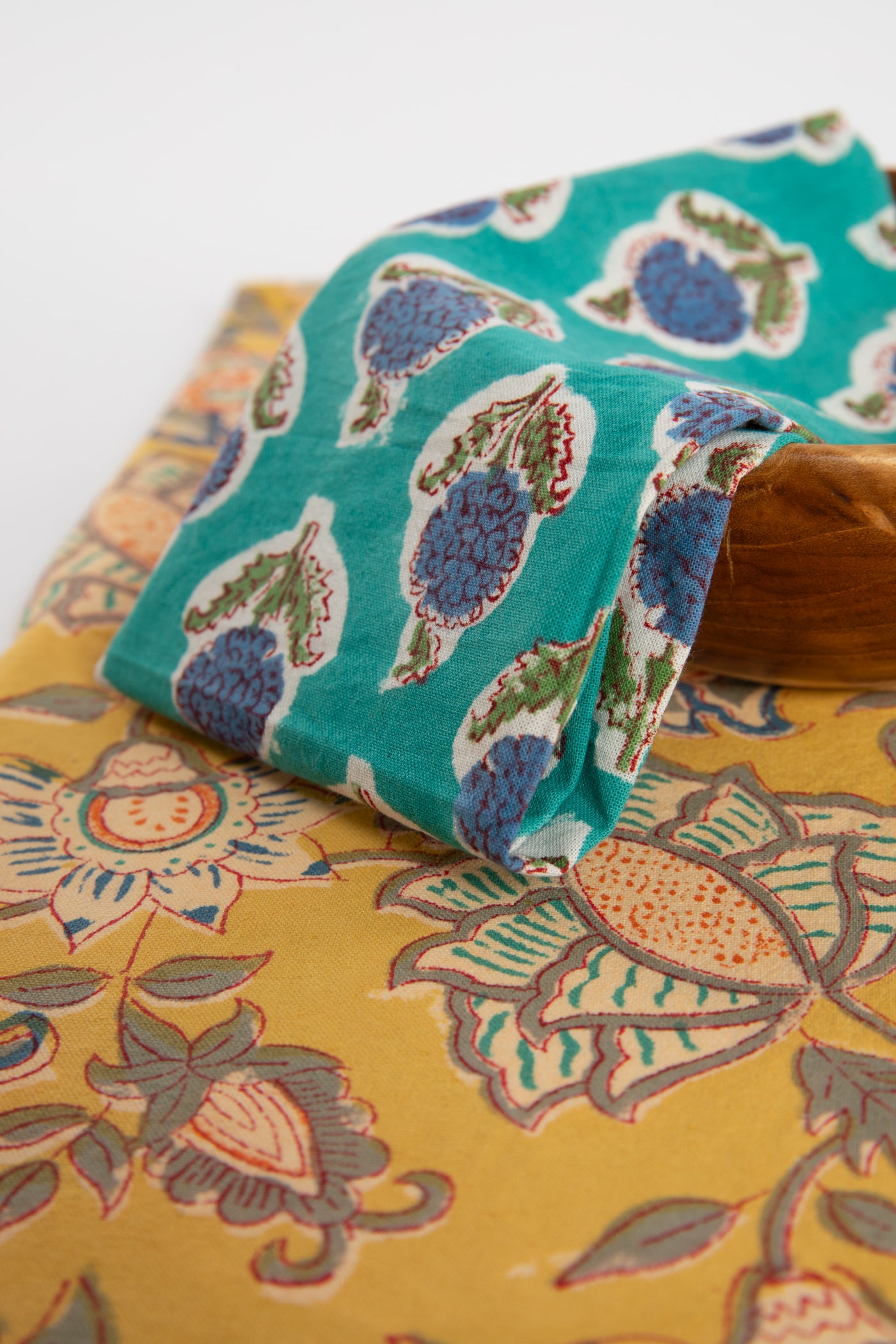 Turquoise block print napkin on teak plate and block print placemat