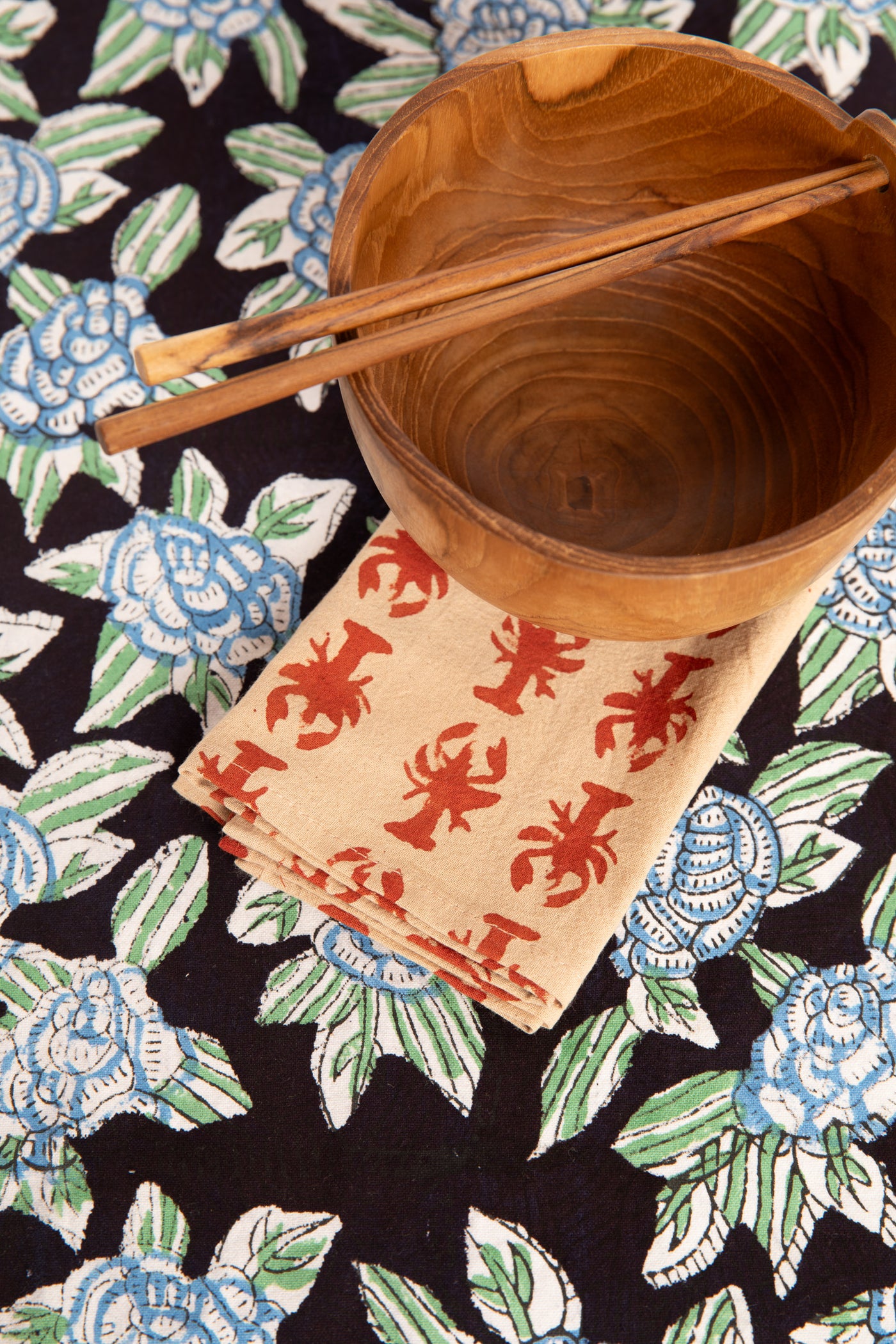 Black floral block print placemat under teak bowl and block print napkin 