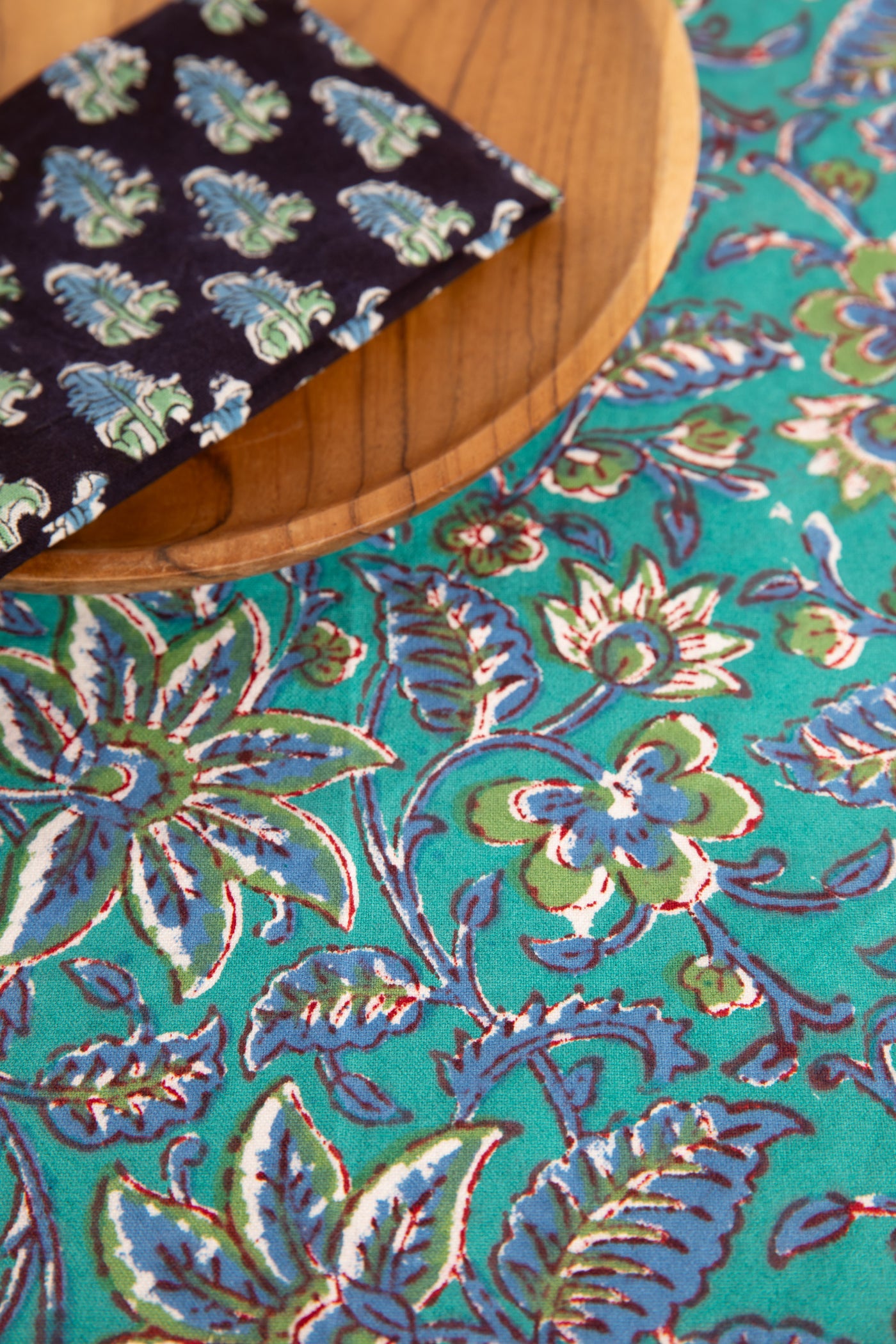 Turquoise floral block print placemat under teak plate and block print napkin 