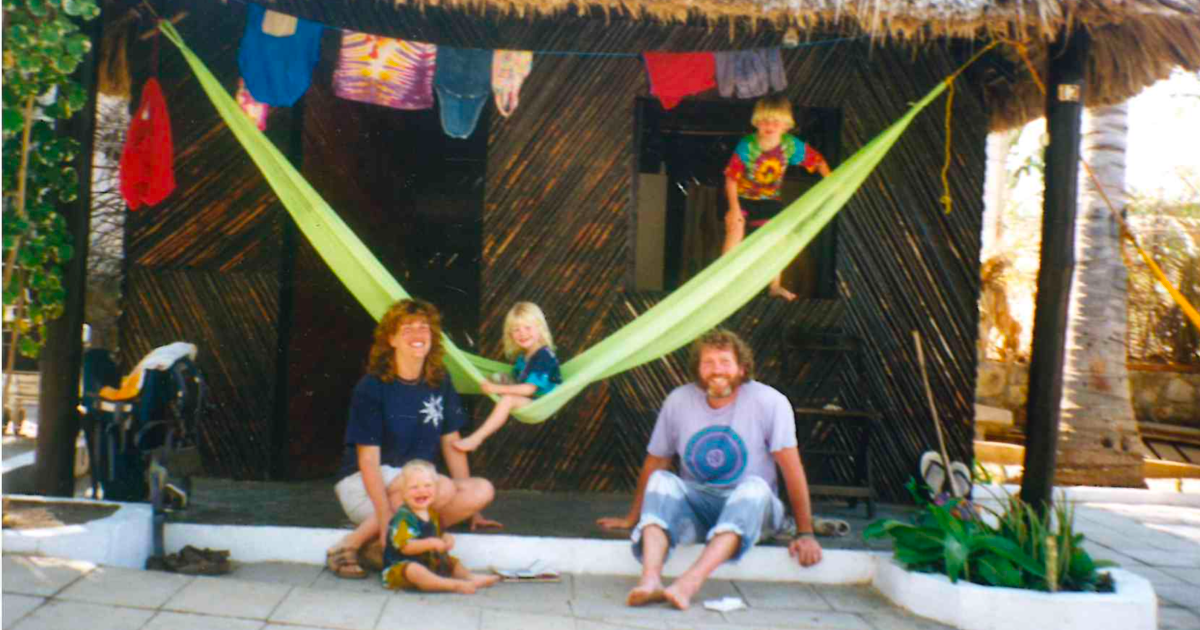 Mexicali Blues owners Pete and Kim with their three hippie children and all of their hippie kids clothes on a drying rack in front of a bungalow in Thailand