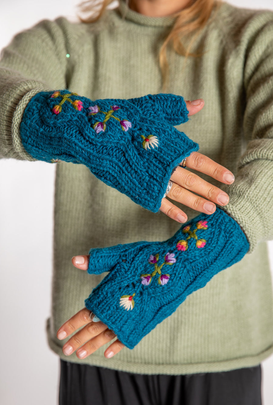 Sophie is wearing the Alpine Flower Fingerless Mittens in Teal