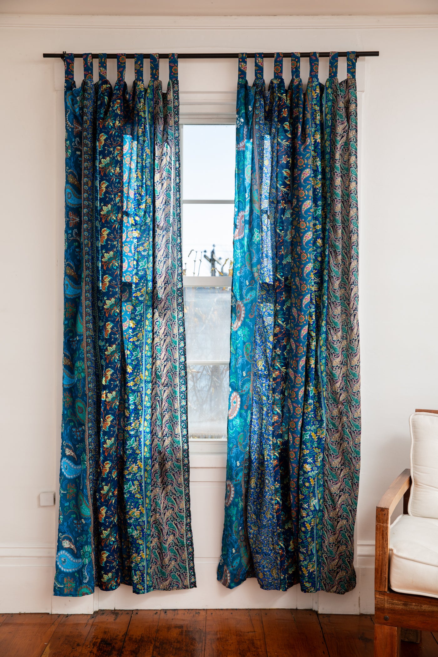 Vibrant blue sari silk curtains hanging in a bohemian living room 