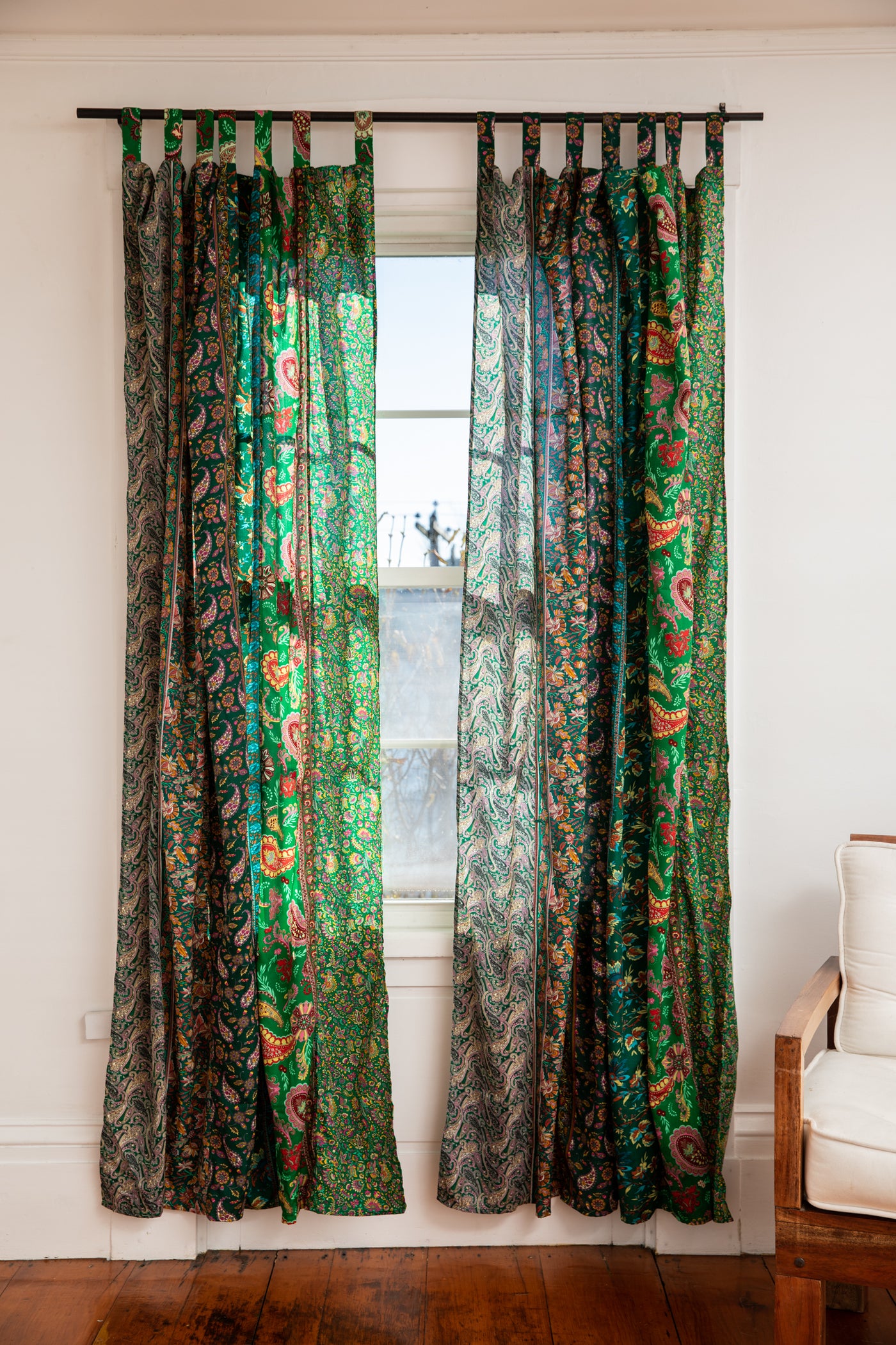 Silk sari curtains in green hanging in a bohemian living room. 
