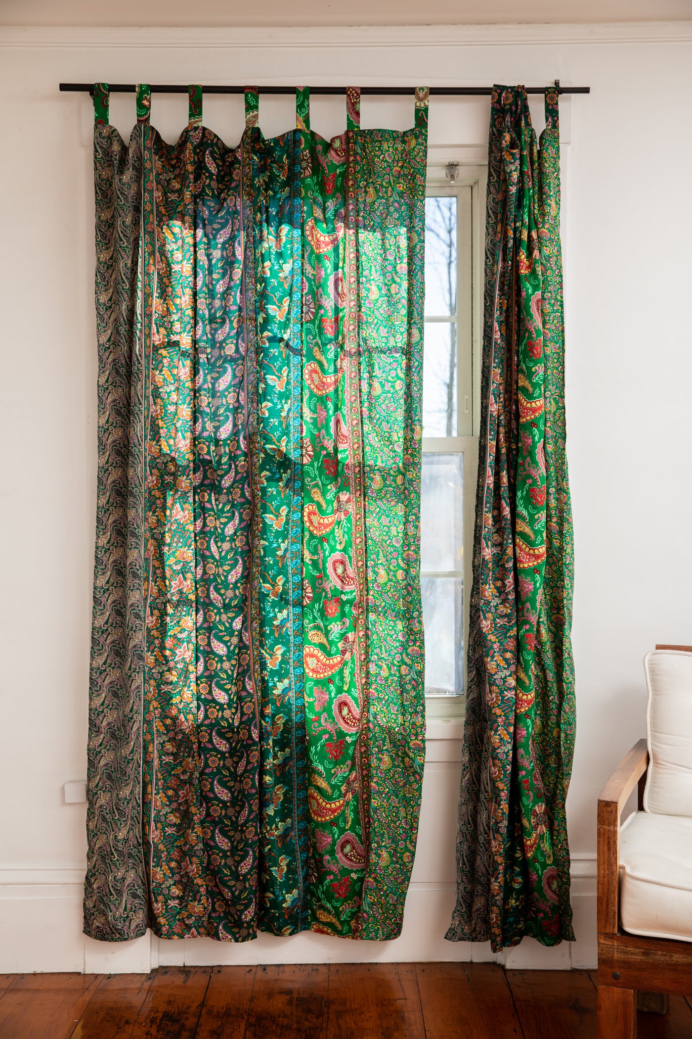 Beautiful green boho curtains hanging in front of a bright window. 