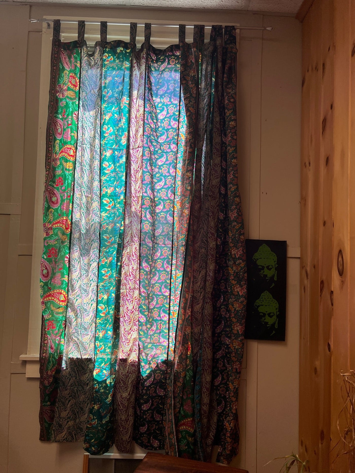Beautiful green boho curtains hanging in front of a window with the sun shining through 