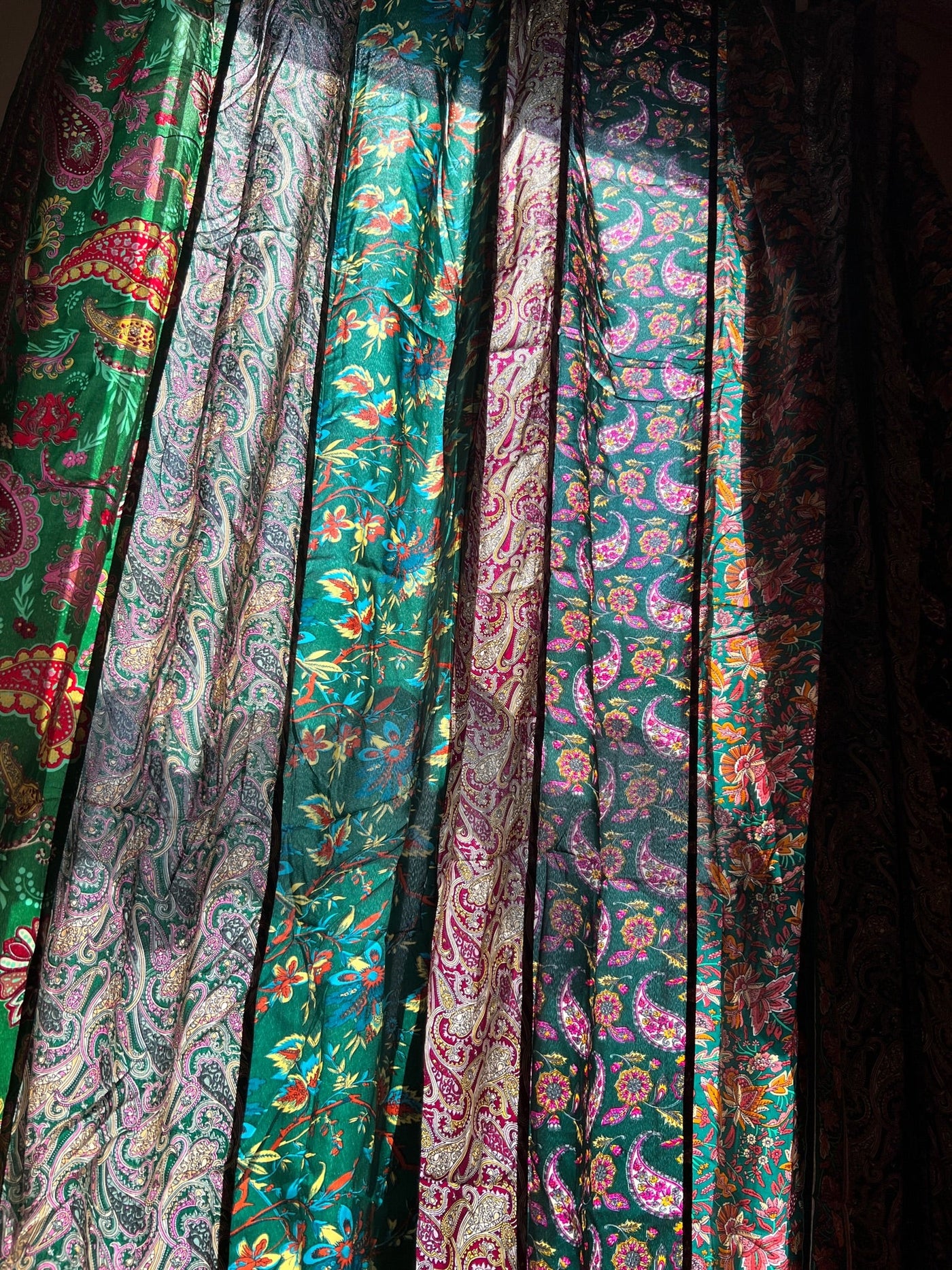 An image showcasing the beautiful and intricate patterns of the sari silk curtains in green with the sun shining through the curtain panel. 