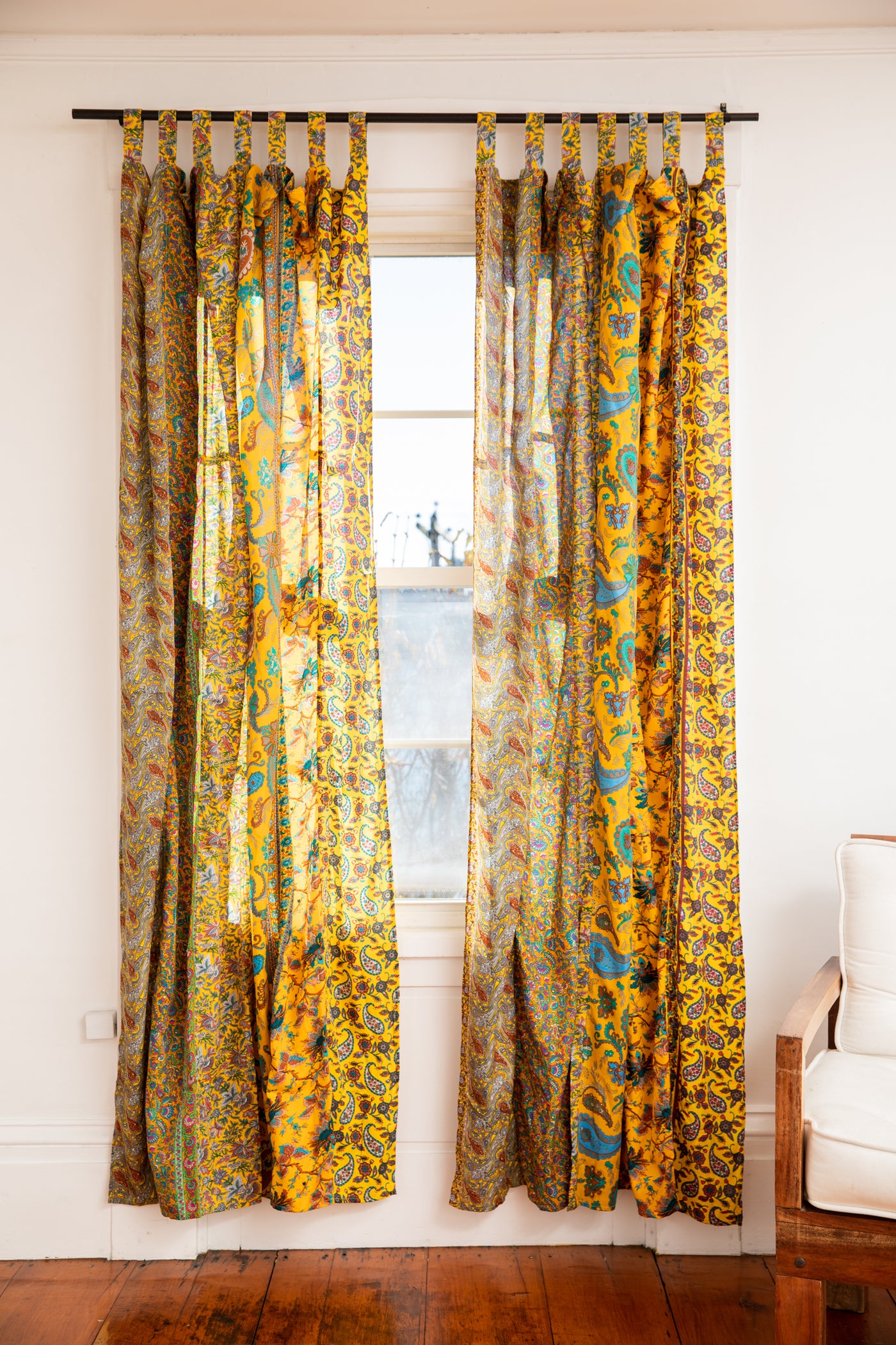 Sunny yellow sari silk curtains hanging in a bohemian living room 