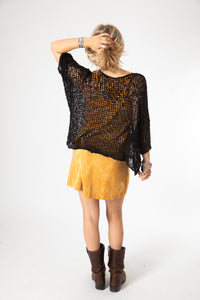 Sophie wearing a black lightweight knitted poncho with a solid pattern.