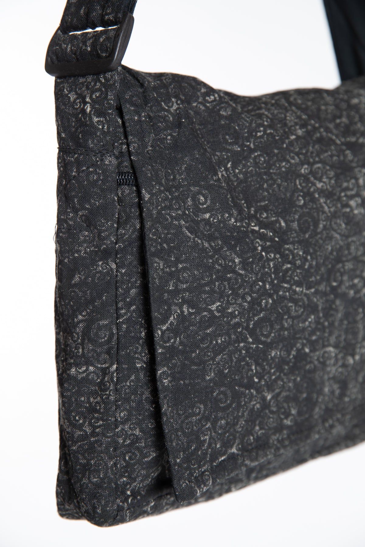 Close-up of the black ebb and flow messenger bag with a subtle gray swirl pattern,
