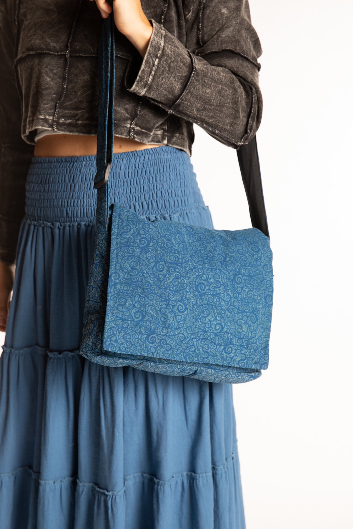 A blue ebb and flow messenger bag with a thick strap, worn crossbody by Sophie