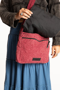 Sophie holding red ebb and flow messenger bag with a black zipper