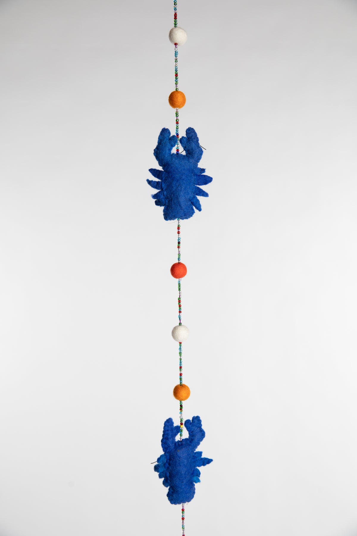 A closeup of a beaded felt blue lobster garland with felt balls 