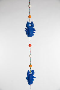 A closeup of a beaded felt blue lobster garland with felt balls 