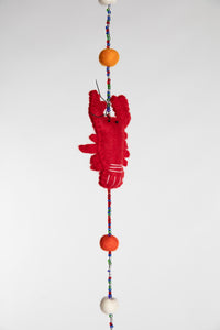 A closeup of a beaded felt red lobster garland with felt balls 