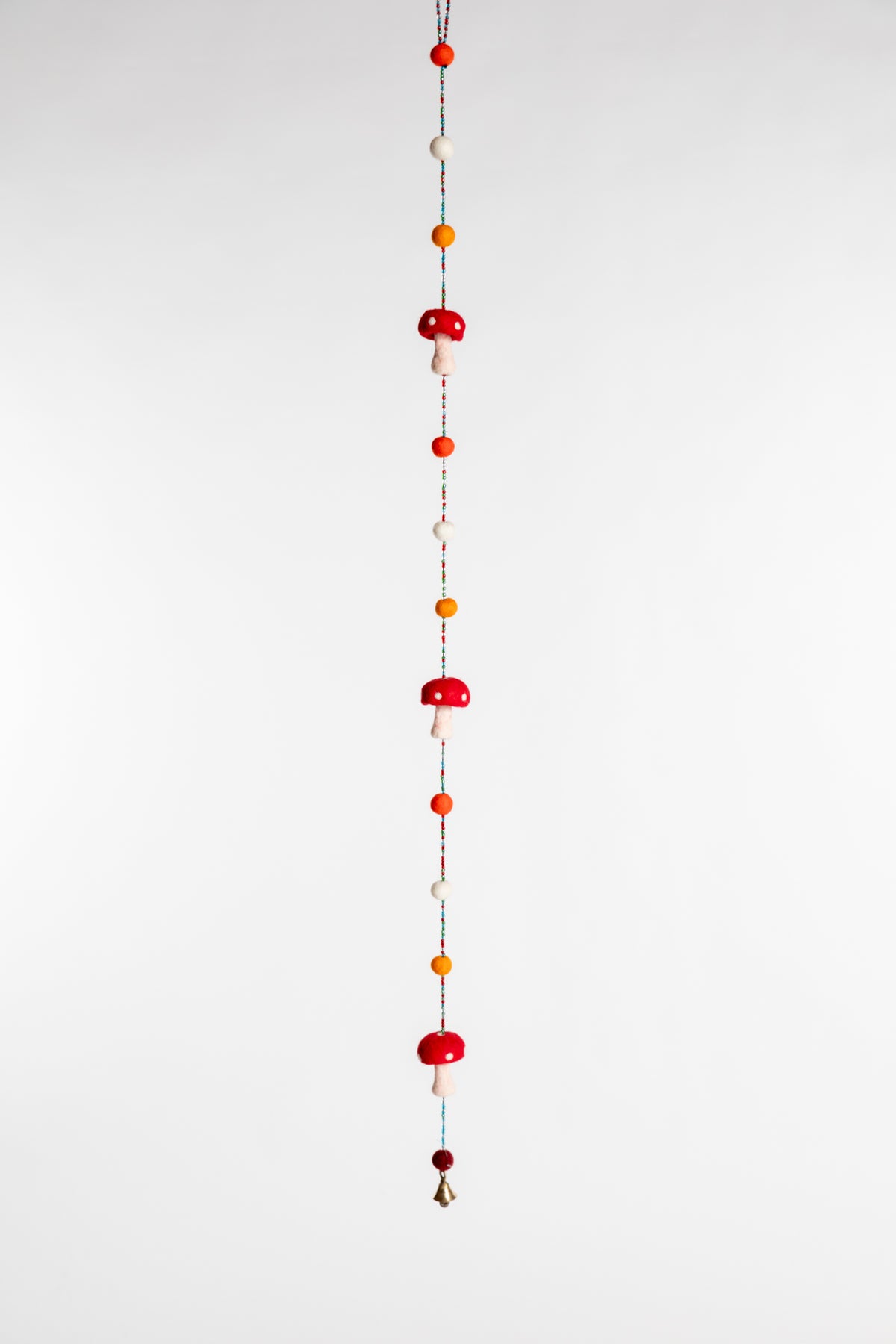 A beaded garland with felt balls and red and white felted mushrooms 