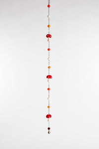 A beaded garland with felt balls and red and white felted mushrooms 