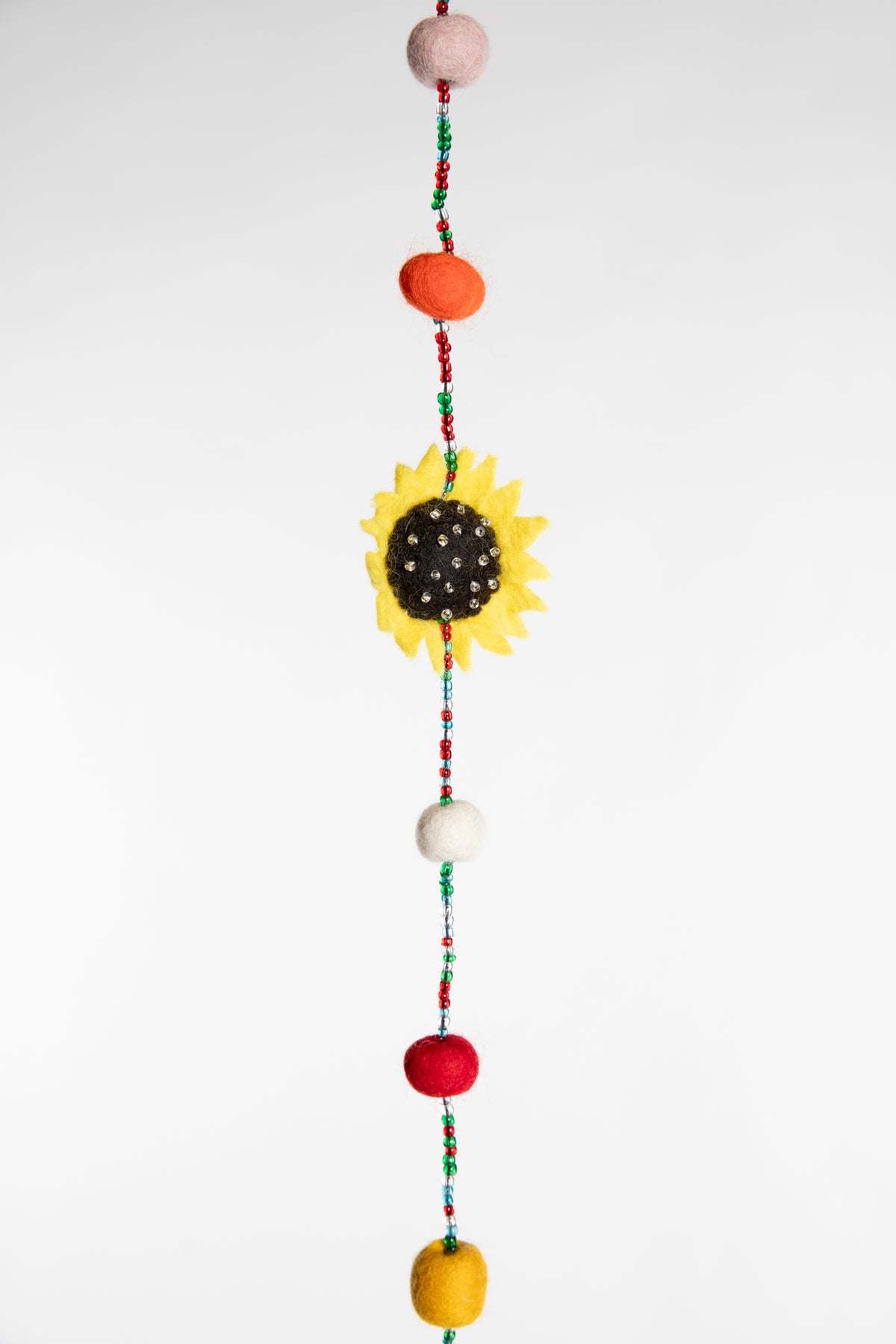 A close up of the beaded garland with felted sunflower and multicolor felt balls