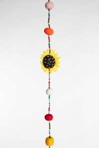 A close up of the beaded garland with felted sunflower and multicolor felt balls