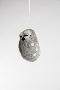 Sideview of a small and grey felted owl with closed eyes