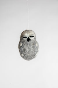 A small and grey felted owl ornament with closed eyes