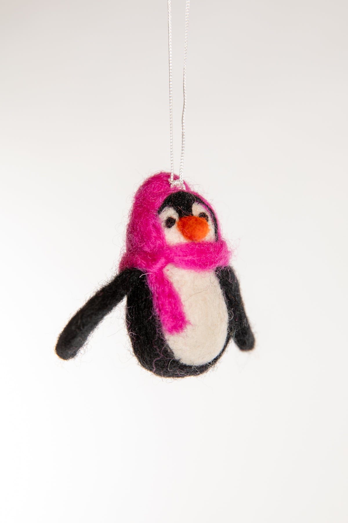 A felted penguin ornament with a pink hat and scarf