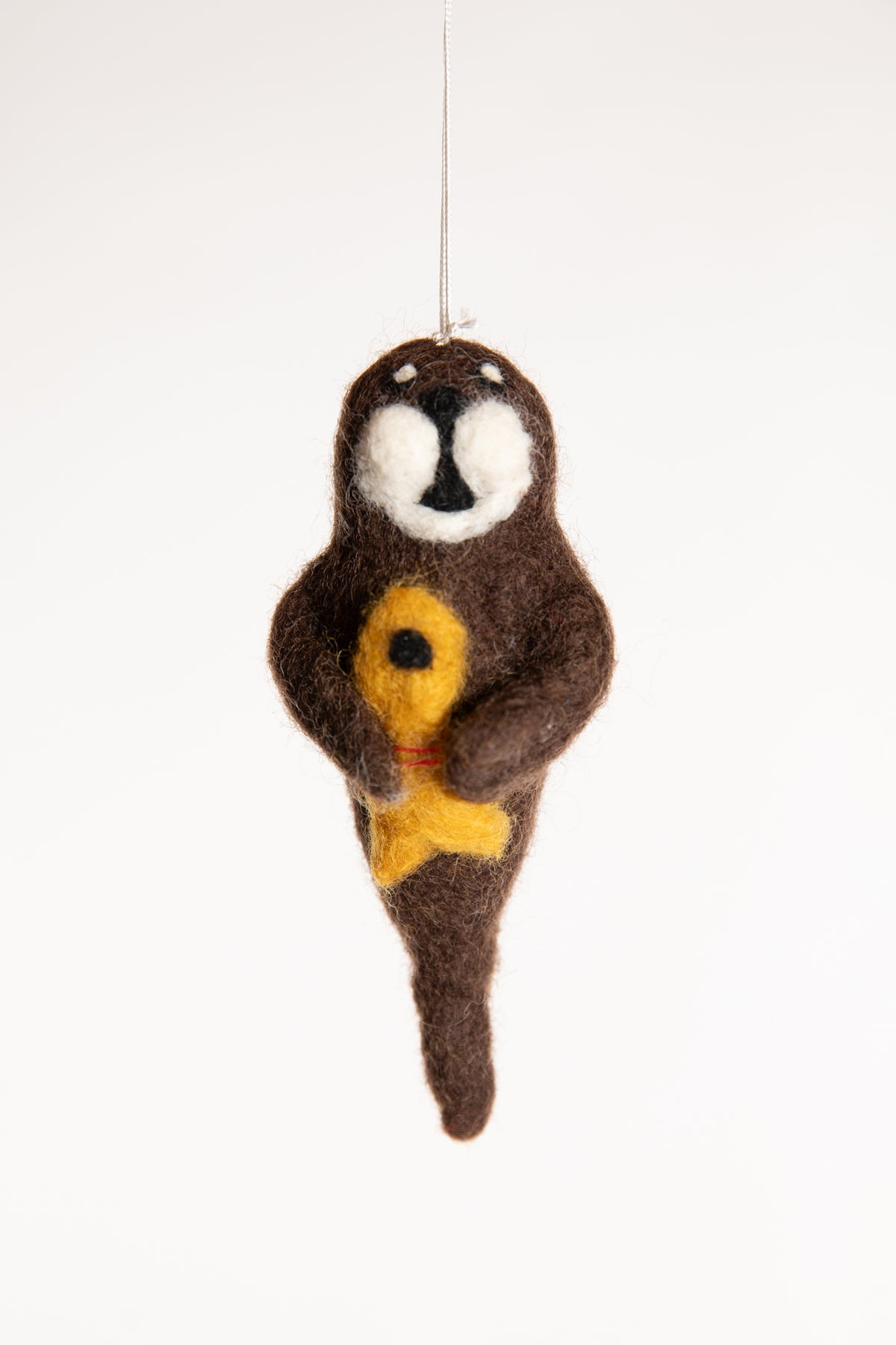 A brown felted walrus ornament holding a yellow fish