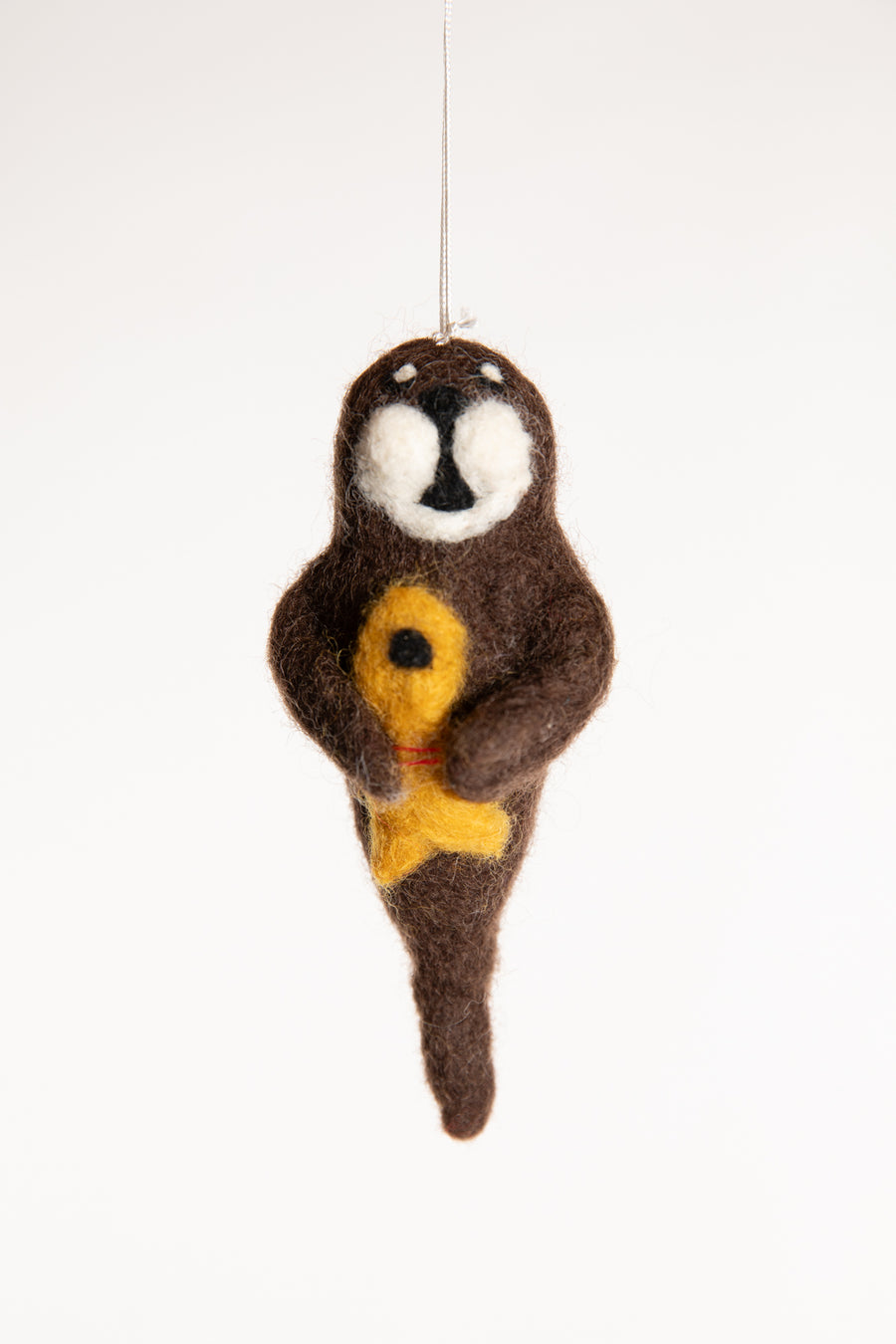 A brown felted walrus ornament holding a yellow fish