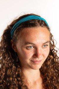 Emily is wearing the Indra Stretch Headband in Teal