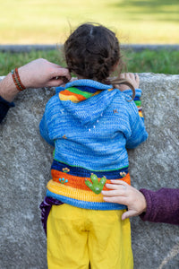 Lilly is wearing a kids nature scene sweater in blue
