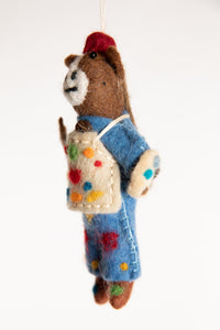 A felted horse ornament with blue overalls, holding a palette and wearing a painter's apron