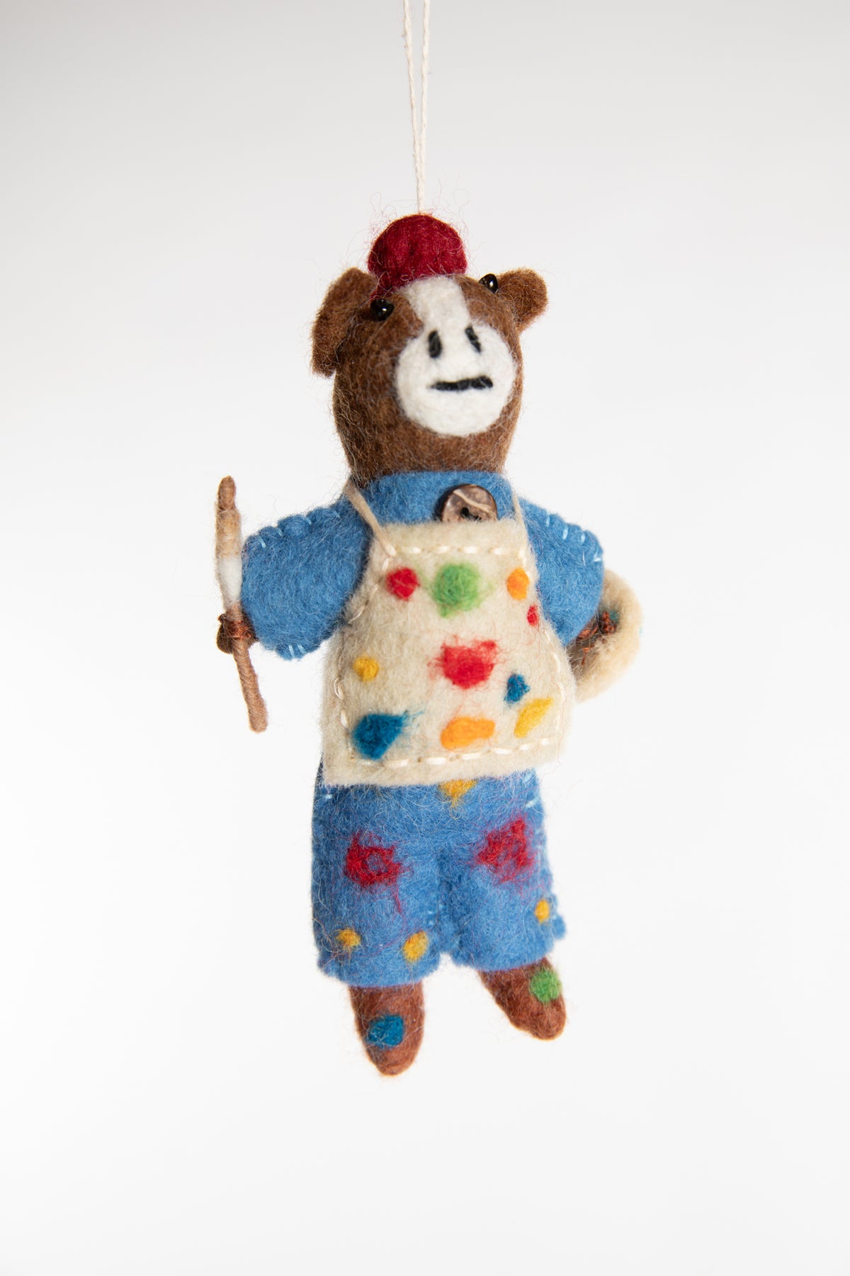 A felted horse ornament with blue overalls, holding a palette and wearing a painter's apron covered in paint spots