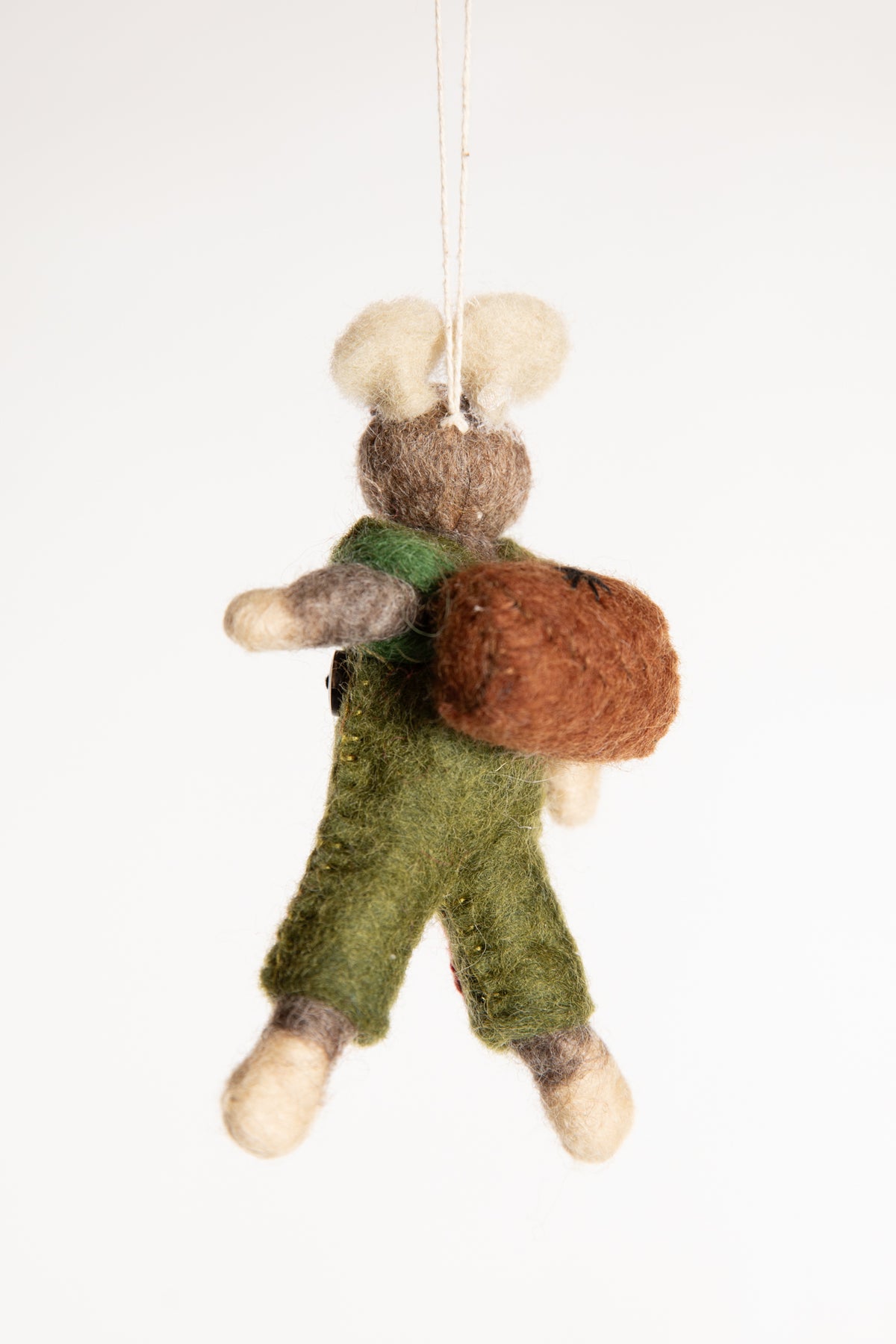 The backside of a felted wool mouse ornament carrying a brown backpack and wearing green overalls