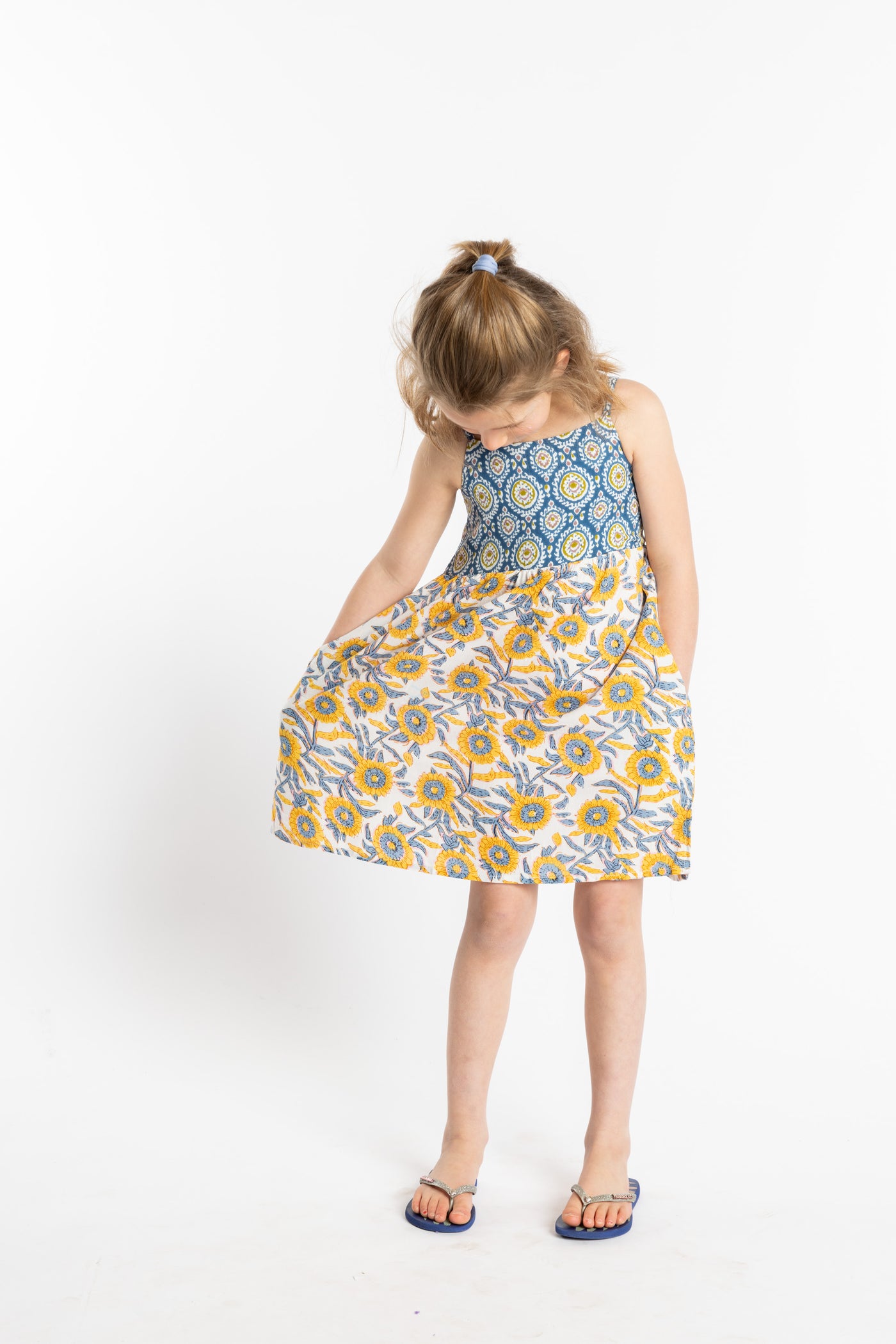 Louisa is wearing the size M sunflower floral kids dress with smocked back
