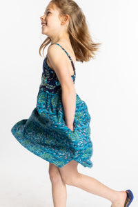 Louisa is wearing the size M teal floral kids dress with smocked back