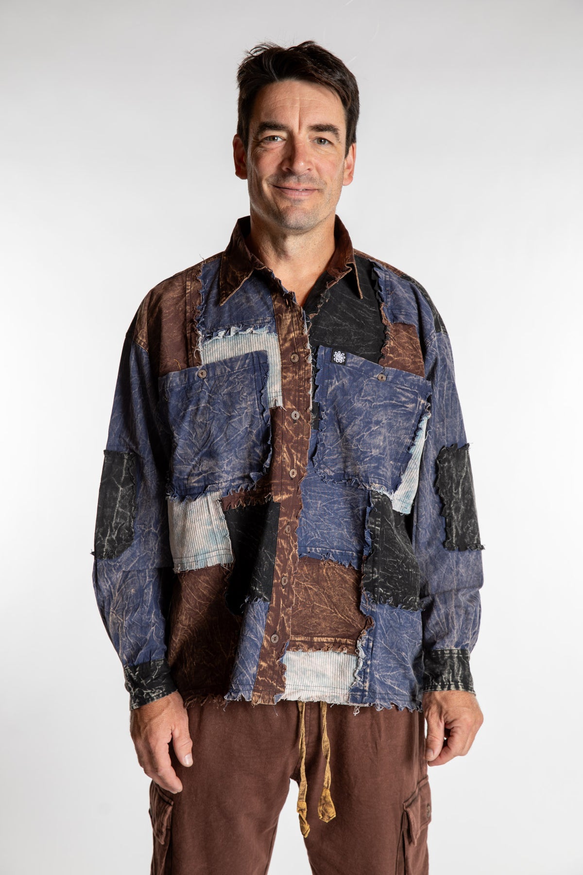 Topher is wearing the One Size Makalu Patchwork Overshirt in North Sea