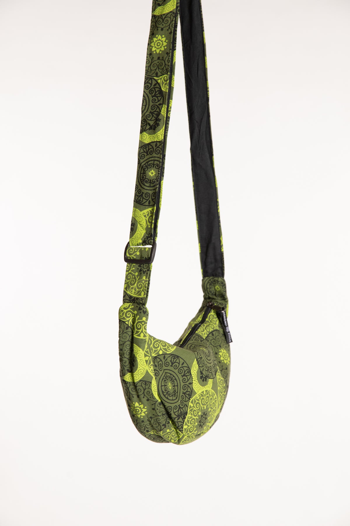 Side view of green mandala crescent bag showing curved silhouette and adjustable strap