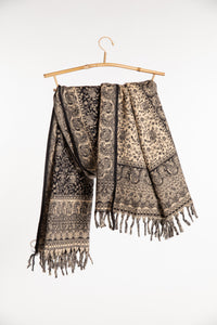 The black paisley soft brushed shawl draped over a wooden hanger against a plain white background.