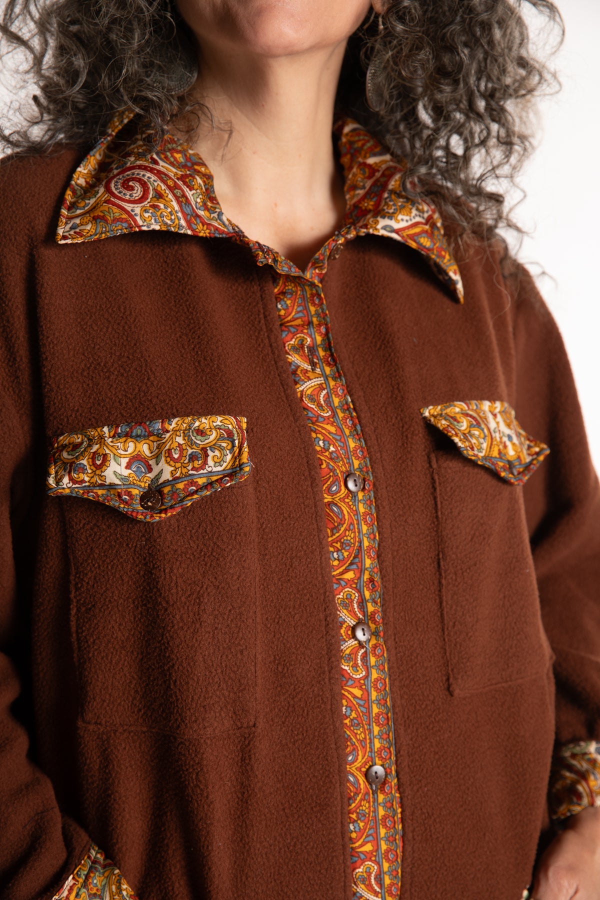 Susan is wearing the M/L Priya Patch Fleece Jacket in Rust