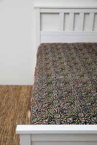 Bohemian block print tapestry in Midnight Vines, displayed as a bedspread