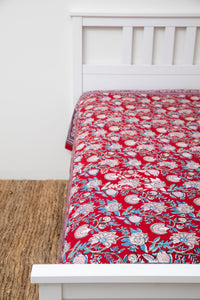 Bohemian block print tapestry in Ruby Reverie, displayed as a bedspread