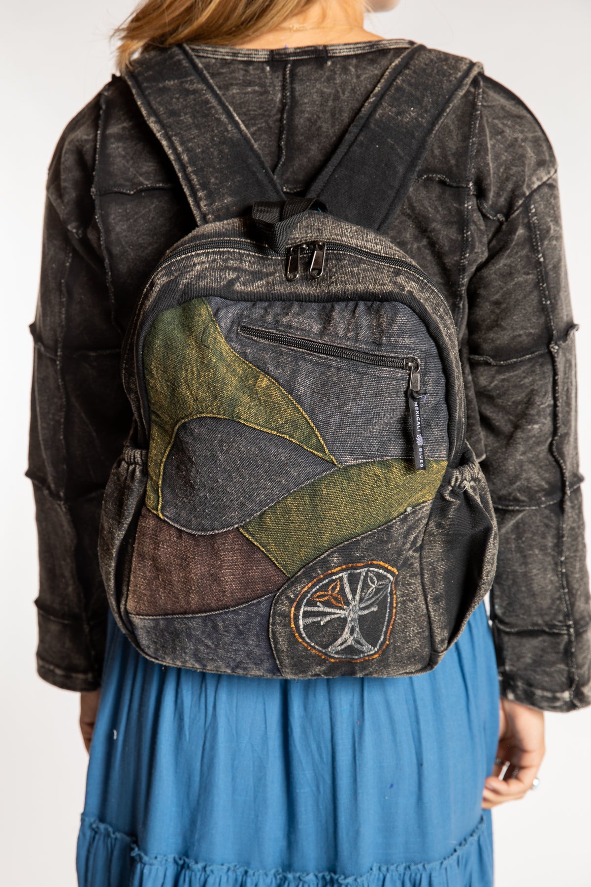 Model wearing black patchwork cotton backpack with contrasting patterned fabric panels