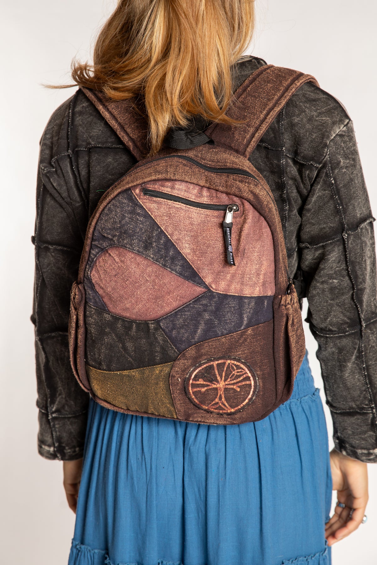 Model wearing brown patchwork backpack with adjustable shoulder straps